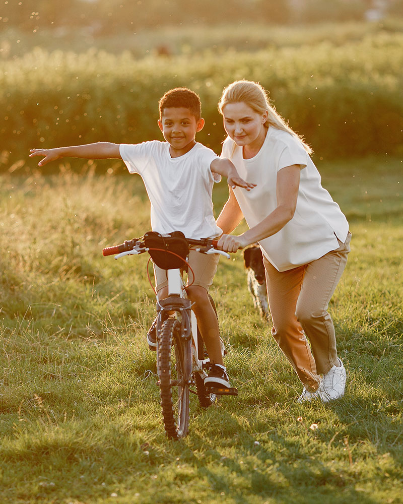 Woman helps a boy riding his bike